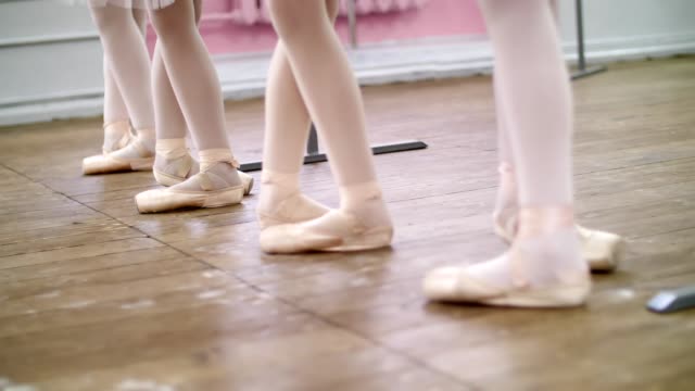 in-ballet-hall,-Young-ballerinas-perform-battement-tendue-back-in-pointe-shoes,-close-up