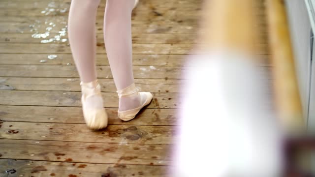 close-up,-in-dancing-hall,-ballerina-in-ballet-shoes-performs-tendu-aside,-grand-battement,-elegantly,-standing-near-barre-at-mirror-in-ballet-class
