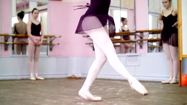 in-dancing-hall,-Young-ballerina-in-black-leotard-performs-glissade-en-tournant,-She-moving-through-the-ballet-class-elegantly