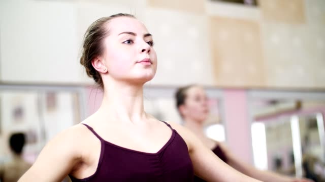 im-Tanzsaal,-führt-junge-Ballerina-in-lila-Anzug-eine-gewisse-Ballett-Übung,-die-erste-Position-der-Hände