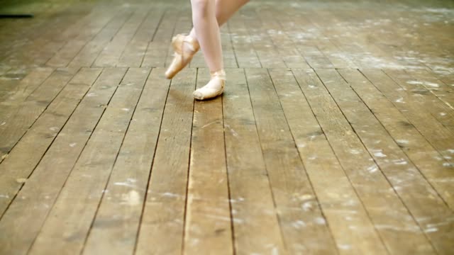 in-der-Nähe,-im-Tanzsaal,-Ballerina-führen-Schritt-Pointe,-sie-steht-auf-Zehen-in-Pointe-Schuhe-elegant,-auf-einem-alten-Holzboden-in-Ballett-Klasse