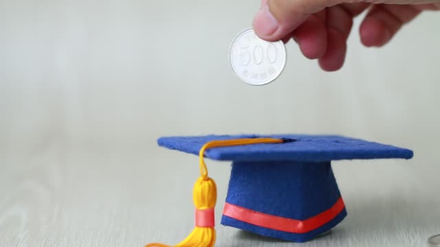 Student-hand-dropping-investing-South-Korean-won-money-coin-to-Graduation-fund-for-save-moneys-in-studying-abroad.-Education-savings-and-investment-ideas