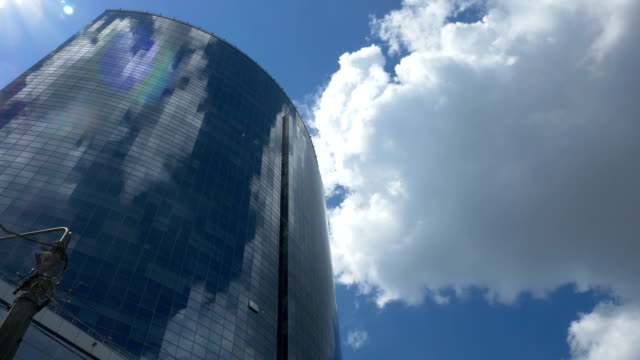 Vista-desde-abajo-en-un-centro-de-negocios-de-vidrio-sobre-un-fondo-de-nubes-grises-en-movimiento.-Reflejo-en-el-vidrio