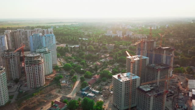 Aerial-drone-shot.-Construction-of-high-rise-buildings-in-the-developing-area-of-a-large-city.-Sunset-shot.-Construction-sites,-houses-handed-over,-construction-cranes-and-many-houses-under-construction.-wide-shot
