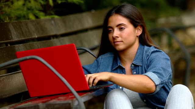 Mujer-escribiendo-en-un-ordenador-portátil-en-un-parque