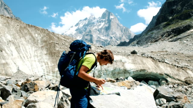 Turística-guía-de-un-hombre-con-una-mochila-que-estudiar-la-ruta-en-el-mapa-y-el-GPS-del-teléfono-en-la-caminata-de-montaña
