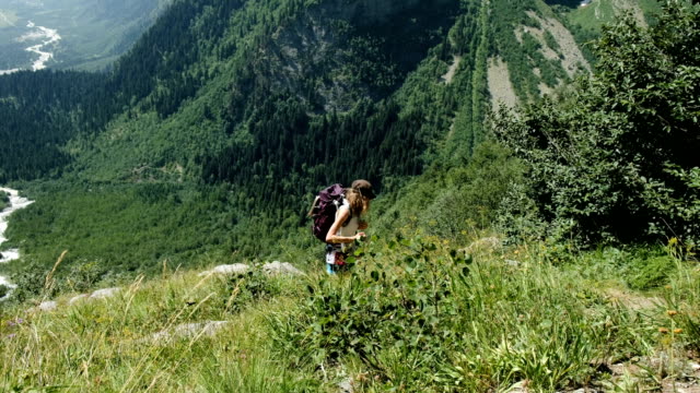 Woman-climber-hiker-tourist-rises-uphill-in-the-background-of-beautiful-scenery