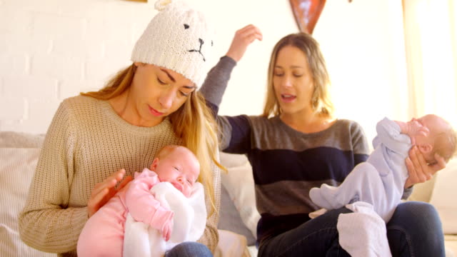 Lesbian-couple-comforting-their-baby-in-living-room-4k