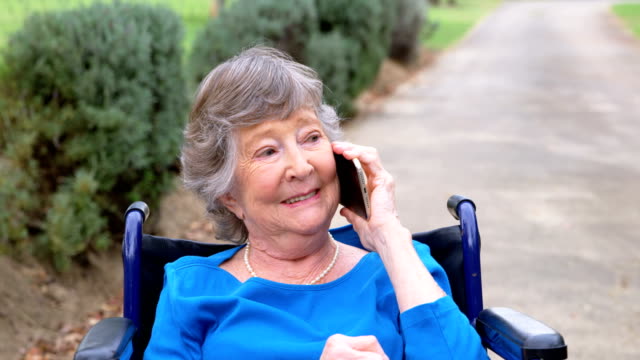 Ältere-Frau-am-Handy-auf-Rollstuhl-4k
