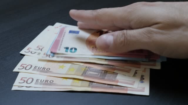 Taking-from-table-by-hand-lot-of-European-Union-currency-lot-4K-3840X2160-UltraHD-video---Wad-of-Euro-money-paper-banknotes-taking-4K-2160p-30fps-UHD-slow-tilt-footage
