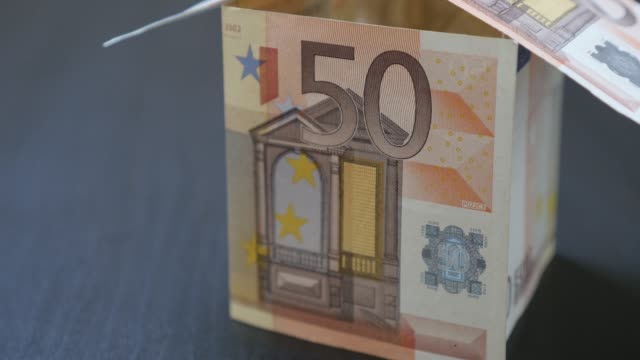 Abstract-house-made-of-Euro-paper-money-of-50-value-bills-close-up-4K-2160p-30fps-UltraHD-video---Zooming-to-fifty-Euros-banknotes-made-house-4K-3840X2160-UHD-footage
