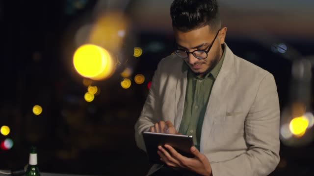 Junge-arabische-Mann-mit-Tablet-auf-Dach-in-der-Nacht
