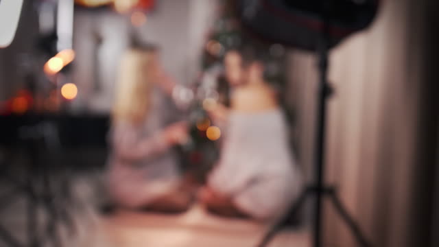 Defocus-Two-multiracial-girlfriends,-with-large-glasses-and-wine-in-their-hands.-During-a-studio-photo-shoot-or-at-home.-Asian-and-Caucasian-women.-Concept-of-female-friendship,-lgbt-and-celebration-of-Christmas.-4k,-slow-motion