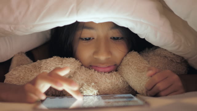 Little-girl-using-tablet-in-the-bedroom.