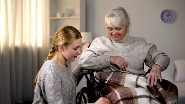 Nieta-con-cuidado-cubriendo-discapacitados-a-abuela-con-manta,-de-apoyo