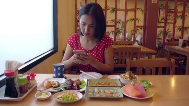 Young-Asian-Woman-Taking-Photo-and-Selfie-with-Salmon,-Chicken,-Sashimi-Japanese-Food.