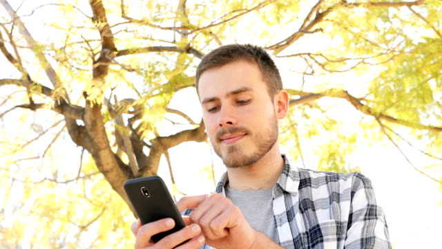 Glücklicher-Mann-mit-Smartphone-in-einem-Park