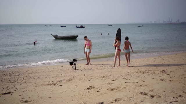 funny-cute-male-gay-metrosexual-in-a-pink-t-shirt-and-blue-shorts.-family-shoots-video-on-the-beach