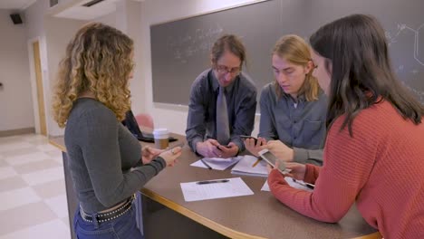 Professor-and-three-students-all-take-out-and-start-using-their-mobile-phones