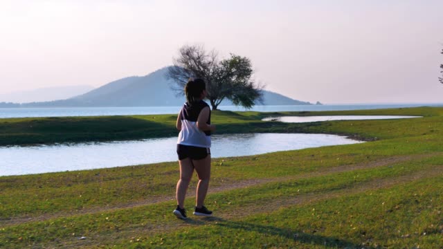 An-Asian-woman-jogging-in-natural-sunlight-in-the-evening.
She-is-trying-to-lose-weight-with-exercise.--concept-health-with-exercise.-Slow-Motion