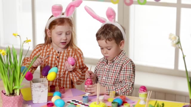 Glückliche-Kinder,-die-am-Ostersamstag-hanzige-Ohren-tragen-und-Eier-malen.-Kleine-Mädchen-bereiten-sich-auf-das-Osterfest-vor.
