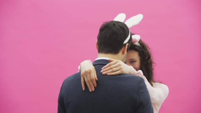 Beautiful-young-girl-standing-on-a-pink-background.-During-this,-there-are-ears-of-rabbits-on-the-head.-Swing-heads-to-each-other-like-bunnies.