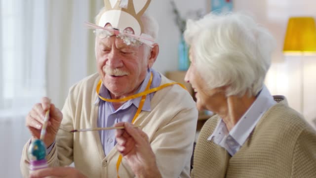 Elderly-Couple-Painting-Eggs-and-Smiling