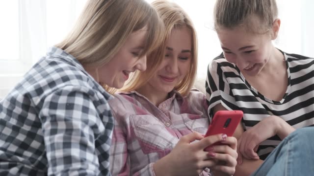 Chicas-adolescentes-disfrutando-de-contenido-multimedia-en-el-teléfono-móvil