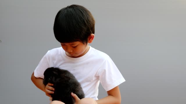 Junge-asiatische-Kind-spielt-mit-lieblichem-schwarzen-Kaninchen