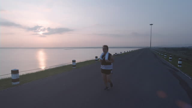 Asian-women-jogging-in-the-street-in-the-early-morning-sunlight-at-water-storage-Pa-Sak-Jolasid-Dam.-concept-of-losing-weight-with-exercise-for-health.-Slow-motion