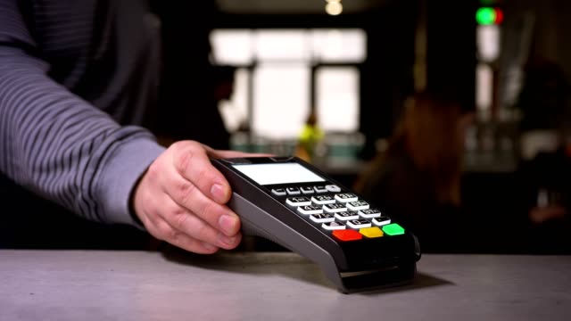 Nahaufnahme-der-Frau-mit-Terminal-und-Kreditkarte-führt-kontaktlose-Paypass-Zahlung.