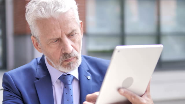 Viejo-empresario-usando-tableta,-al-aire-libre
