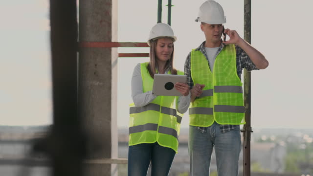Der-Controller-ist-ein-Mann-eines-Gebäudes-im-Bau-sprechen-am-Telefon-mit-dem-Management-und-hat-mit-dem-Ingenieur-und-Architekt-Frau-Baufortschritt-diskutiert