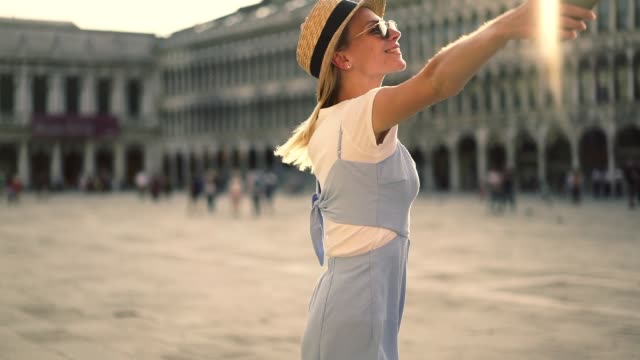Aufgeregt-hübsche-Hipster-Mädchen-Spinnen-auf-dem-Platz-in-Rom-genießen-Urlaub-im-Sommer-halten-Smartphone-zufrieden-mit-guter-mobiler-Verbindung-und-4G.