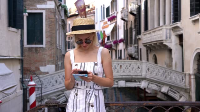 Glückliche-weibliche-Touristin-genießt-die-Kommunikation-mit-Freunden-über-mobile-Anwendung,-während-sie-auf-Venedig-Brücke-ruhen-und-4g-Internet-im-Roaming