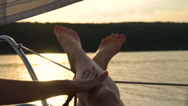 lesbian-hands-touching-legs-of-her-partner-relaxing-on-sailboat