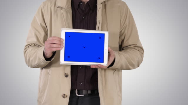 Männliche-Hände-halten-Tablet-mit-blauem-Bildschirm-Mockup-auf-Farbverlauf-Hintergrund