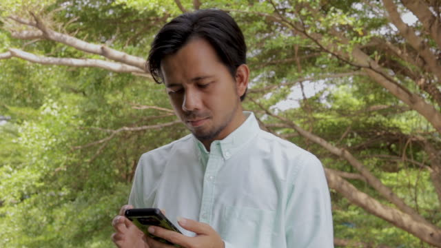 Hombre-asiático-disfrutando-del-éxito-mientras-se-utiliza-Smartphone