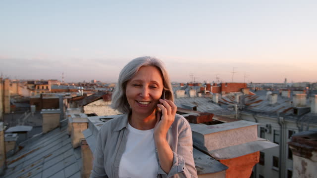 Grauhaarige-Touristin-mit-Telefongespräch-auf-dem-Dach