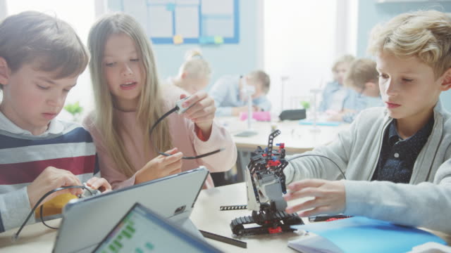 Elementary-School-Robotics-Classroom:-Diverse-Group-of-Brilliant-Children-Building-and-Programming-Robot,-Talking-and-Working-as-a-Team.-Kids-Learning-Software-Design-und-Creative-Robot-Engineering