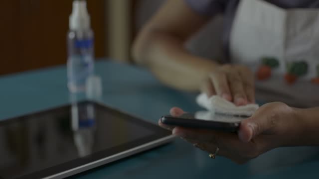 Woman-cleaning-and-disinfection-on-surfaces-of-mobile-phone-and-digital-tablet.