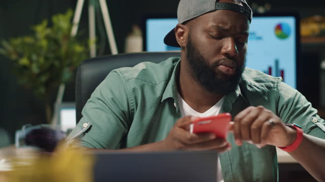 Closeup-young-african-american-man-typing-message-on-mobile-phone-in-hipster-office