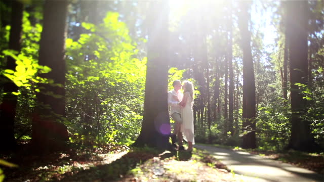 Couple-in-love-in-forest-tilt-shift.-Man-leaning-on-tree-trunk-holds-embracing-beautiful-blonde-woman-in-his-hands-kissing-her-forehead-and-nose.-Sweet-romantic-tenderness-understanding-concept