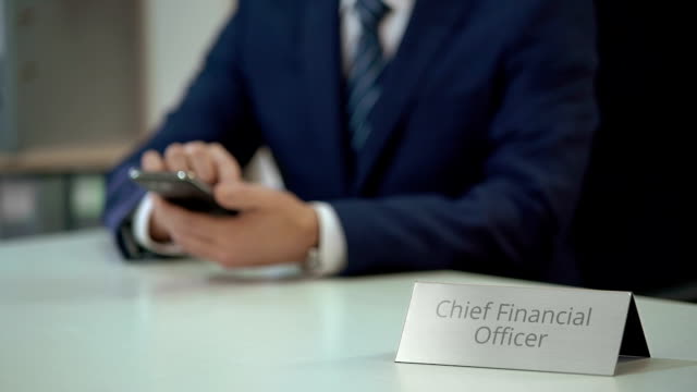 Male-chief-financial-officer-texting-on-smartphone,-viewing-business-files