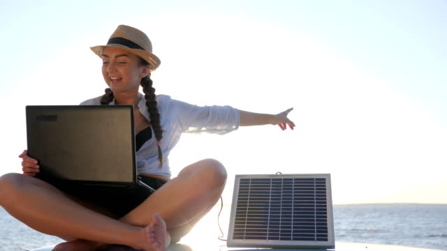 Tourismus,-Mädchen-sitzt-auf-Autodach-bei-Gegenlicht-spricht-über-Laptop-und-Aufladungen-Solargenerator,-junge-Frau-sitzt-auf-Oldtimer