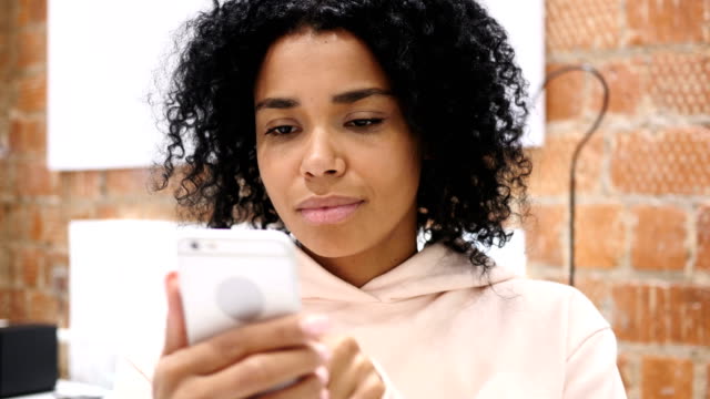 Afro-American-Woman-at-Work-Browsing-Smartphone-in-Office