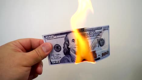 Hand-holding-a-burning-hundred-dollar-banknote