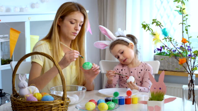 ¡Feliz-Pascua-de-resurrección!-Madre-y-su-pequeña-hija-con-divertidas-orejas-de-conejo-para-colorear-huevos-de-Pascua