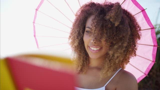 Entspannte-afroamerikanische-Frauen-Buch-unter-Sonnenschirm