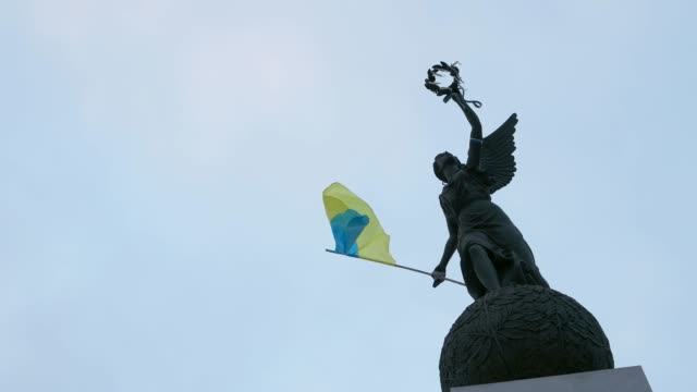 Ukrainian-flag-fluttering-on-independence-monument,-slow-motion